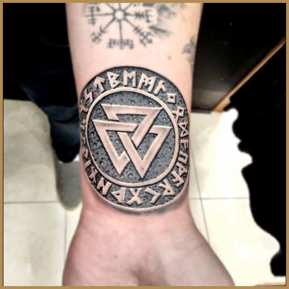 קעקוע של סמל ואלדנוט (Valknut) בתוך מעגל רונות נורדיות על פרק היד