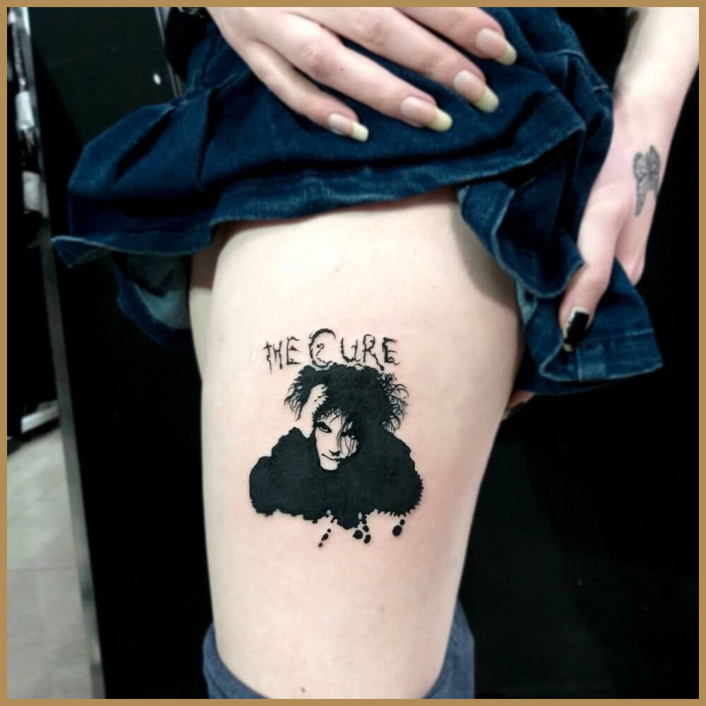 קעקוע שחור של רוברט סמית' מלהקת The Cure עם הכיתוב THE CURE על הרגל